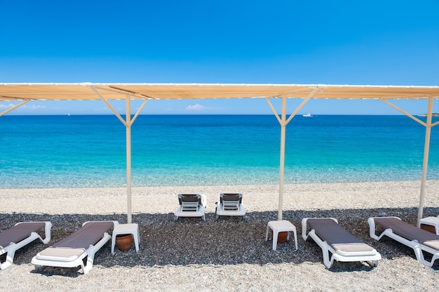 Chaise zitkamers onder de tent op het kiezelstrand in Kemer, Turkije.