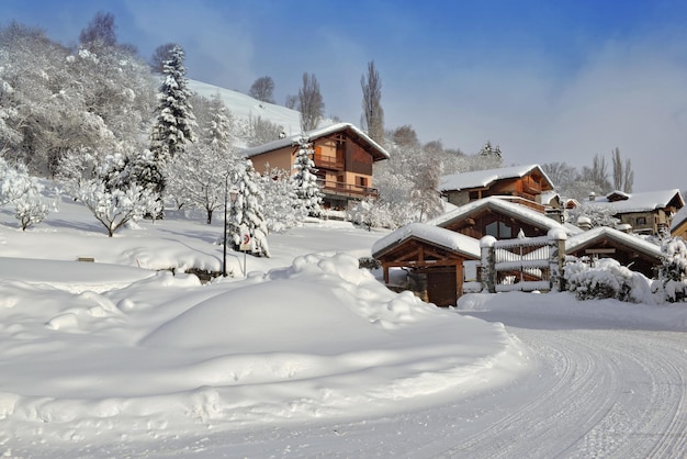 Chalets  in alpine village covered with snow at the end of a white rural road