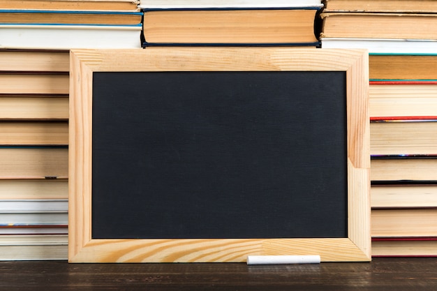 Chalk black board and chalk, against books, copy space.