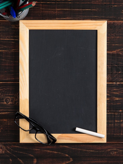 Chalk black board, glasses and chalk on a wooden table, copy space.