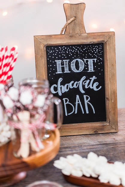 Foto lavagna con cartello per barretta di cioccolata calda con varietà di condimenti.