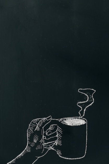 Chalk hand drawing a hand holding coffee cup with steam on black board 