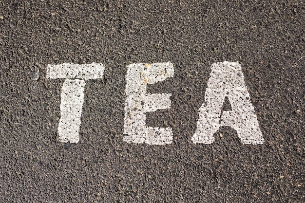 Chalk paint of word TEA on asphalt.