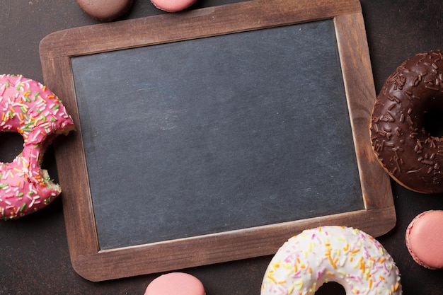 Photo chalkboard and colorful donuts on stone table