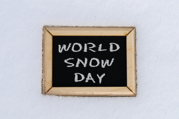 Lavagna nella neve con l'iscrizione - world snow day.