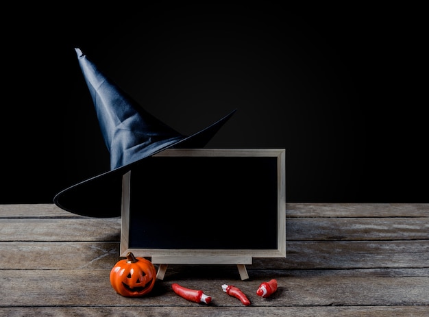 The chalkboard on the stand, Witch hat with Halloween Pumpkins on wooden floor