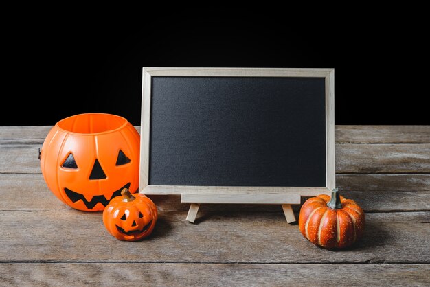 The chalkboard on the stand with Halloween Pumpkins on wooden floor 