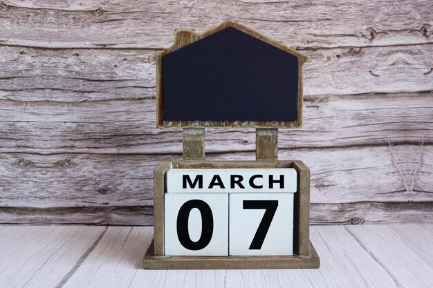 Chalkboard with March 07 date on white cube block on wooden table