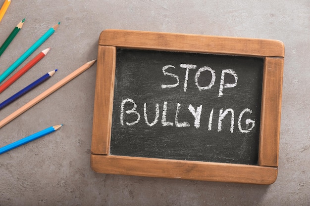 Chalkboard with text STOP BULLYING on grey background