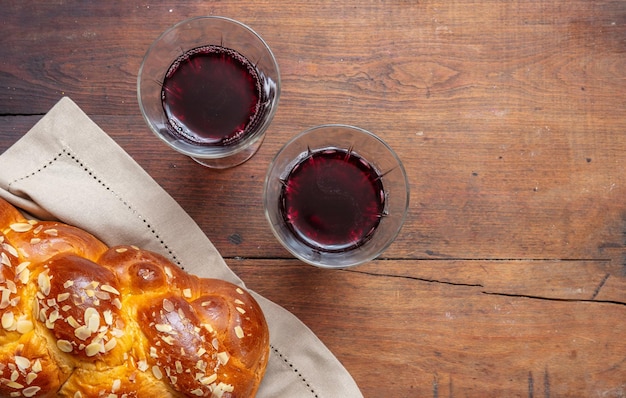 Challah bread with two glasses of red wine on wooden table copy space