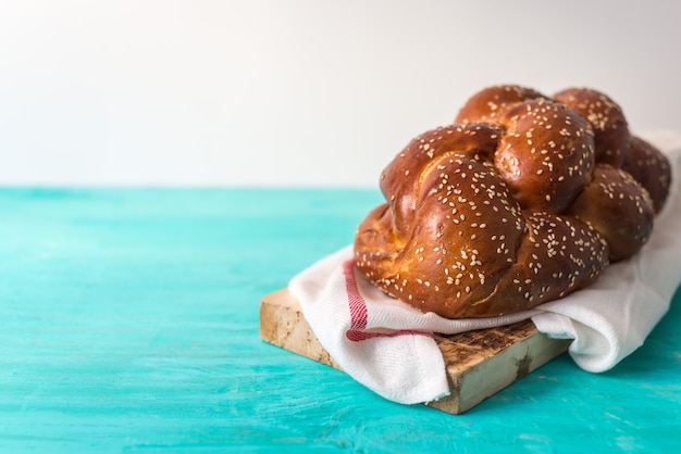 Photo challah bread on a wood plate on wooden table