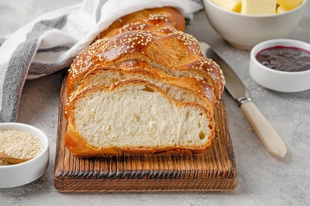 Challah brood met sesamzaadjes boter en jam op een grijze betonnen achtergrond Zoet brood