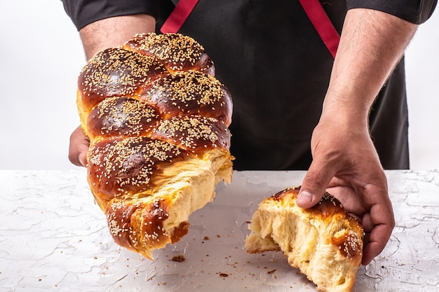 Challah Joods brood in handen van de mens, zelfgemaakt bakken, traditioneel Joods brood, Joodse gebakjes