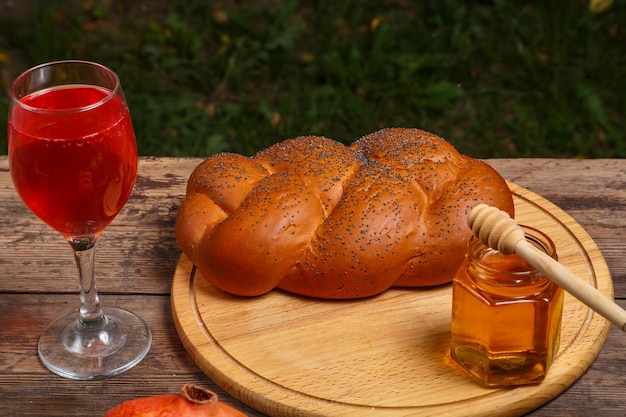 Challah wine in a glass and honey on a wooden table on planks for rosh hashanah