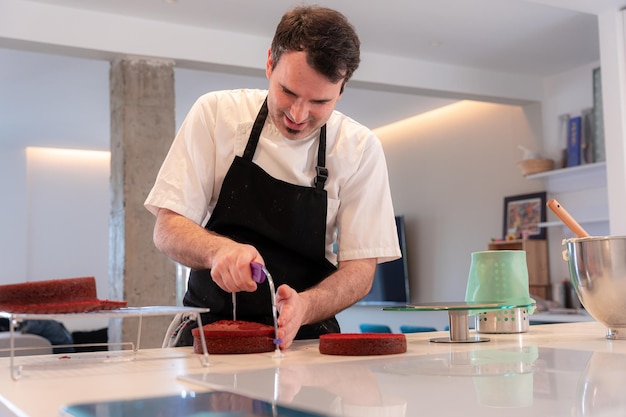 Мужчина-претендент готовит торт "Красный бархат" дома, разрезая пирог, испеченный дома, с помощью лиры