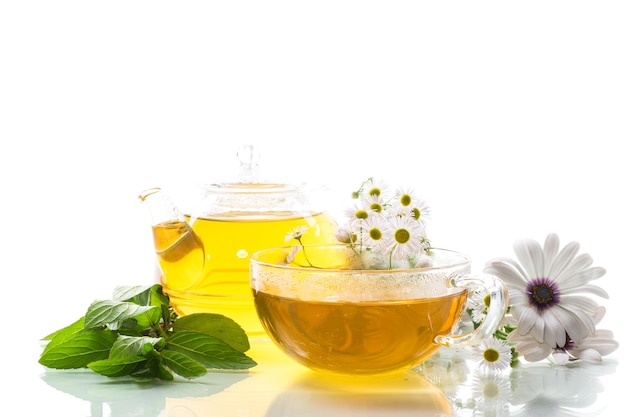 Chamomile flower tea in glass cup and teapot isolated on white background