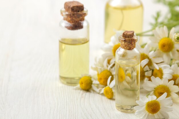 Chamomile. Medicinal little flowers of chamomile with aroma oils on a white wooden table. close-up