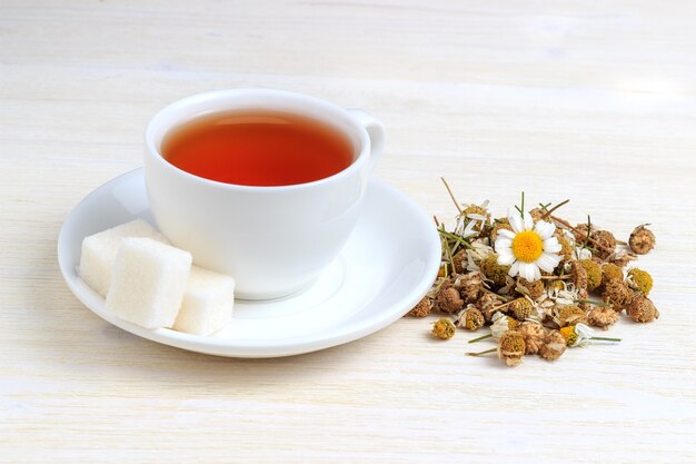 Chamomile tea in a white cup and sugar cubes