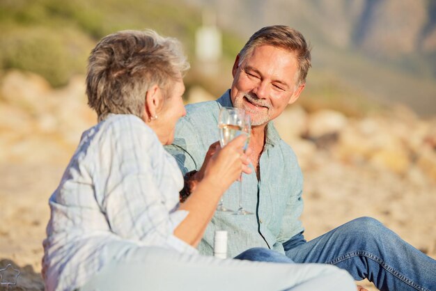 Champagne beach and love celebration of mature couple with care and support of marriage Toast wine and sea picnic of a old man and woman together on holiday in summer loving the sunshine outdoor