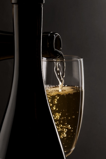 Foto lo champagne viene versato in un flute di champagne con uno sfondo scuro