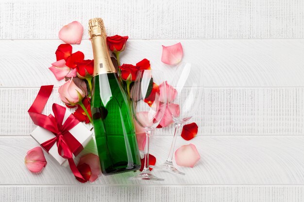 Фото Бутылка шампанского и лепестки цветов роз поздравительная карточка на день святого валентина с подарочной коробкой и местом для ваших поздравлений