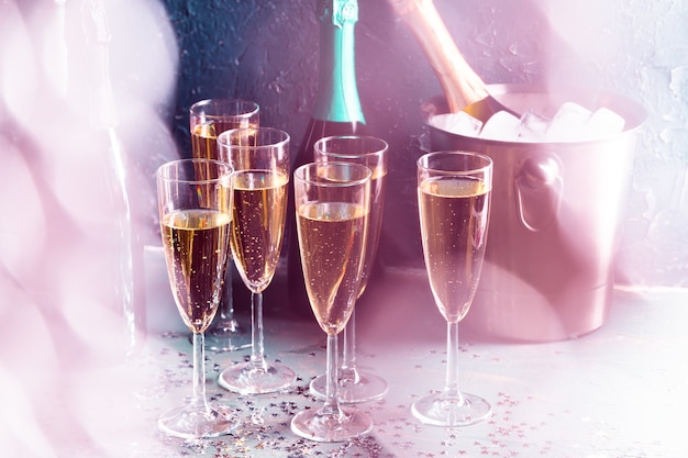 Champagne bottle in bucket with ice and glasses of champagne