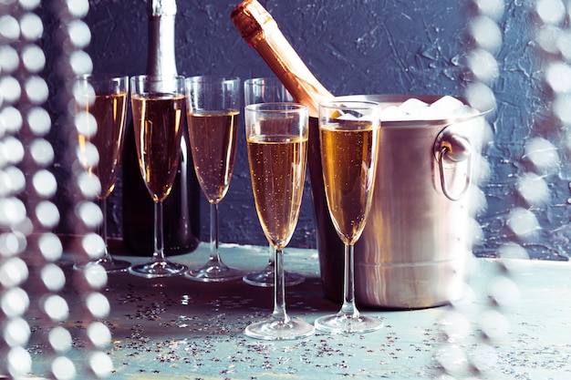 Champagne bottle in bucket with ice and glasses of champagne