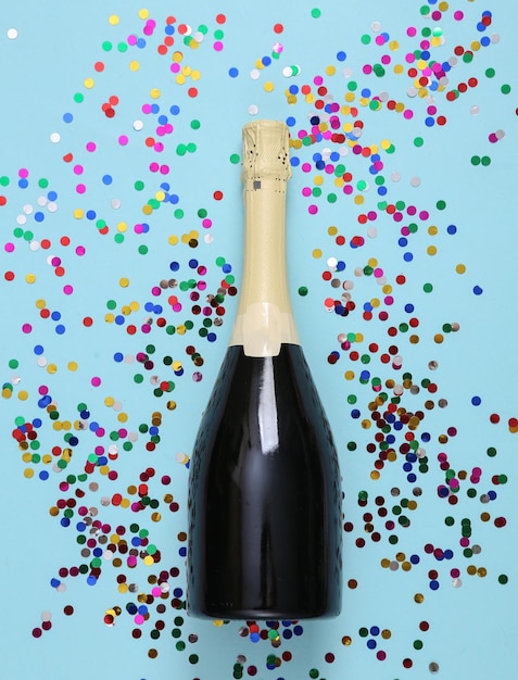 Champagne bottle and confetti on blue background