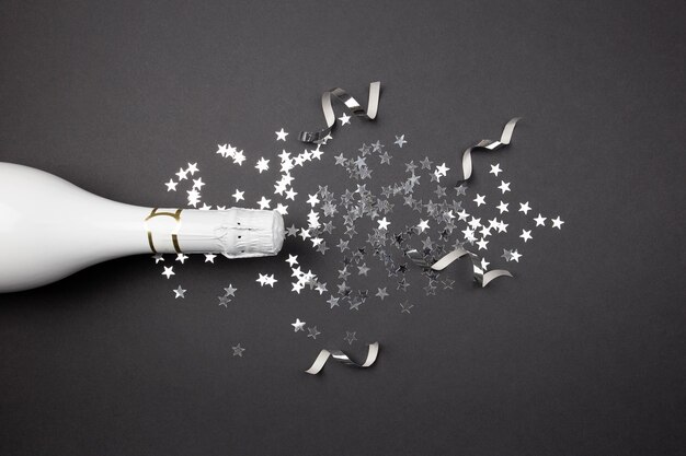 Champagne bottle and confetti on dark surface