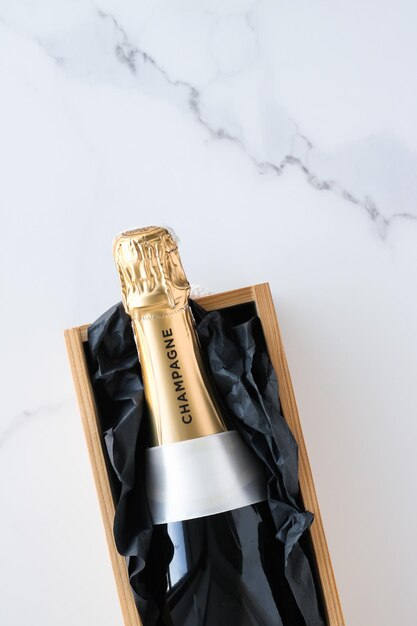 Photo a champagne bottle and a gift box on marble