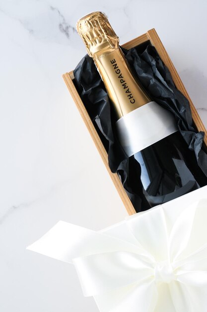 A champagne bottle and a gift box on marble