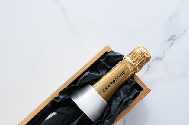 A champagne bottle and a gift box on marble