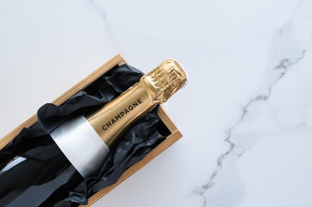 A champagne bottle and a gift box on marble