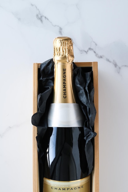 A champagne bottle and a gift box on marble