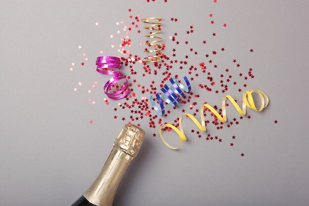 Photo champagne bottle glasses and confetti on a colored background top view