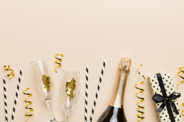 Champagne bottle glitter and straws on color background top view Hilarious christmas and birthday celebration