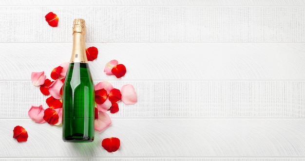 Champagne bottle and rose flower petals Valentines day greeting card with space for your greetings Top view flat lay