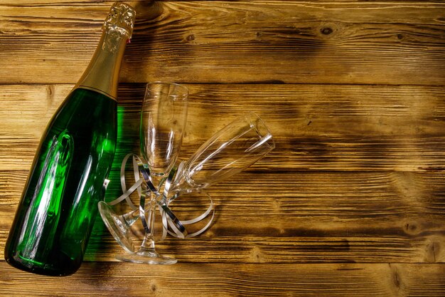 Champagne bottle and two empty champagne glasses on wooden background Top view copy space