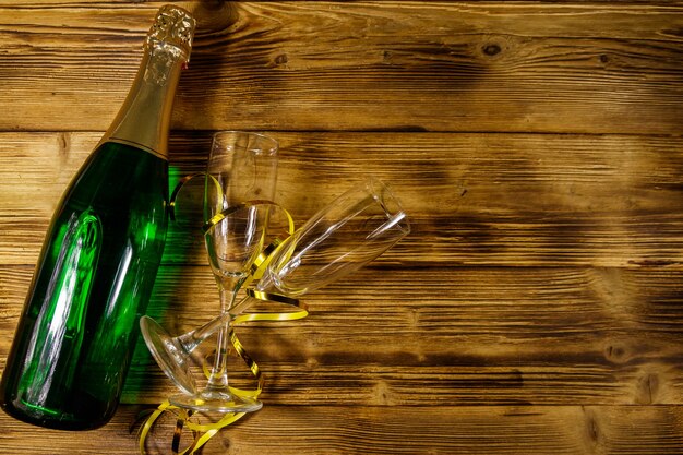 Champagne bottle and two empty champagne glasses on wooden background. Top view, copy space