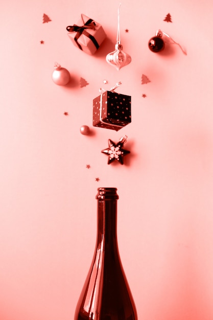 Champagne bottle with different christmas decoration on pink.