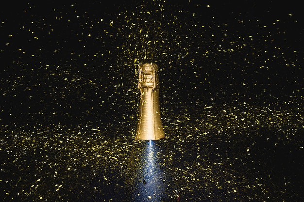 Foto bottiglia di champagne con paillettes che cadono