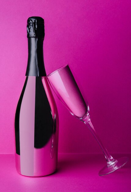 Champagne bottle with glass on pink background