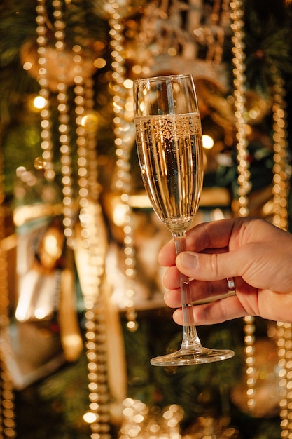 Photo champagne bottle with golden sequin and glasses at sparkling bokeh yellowish garlands