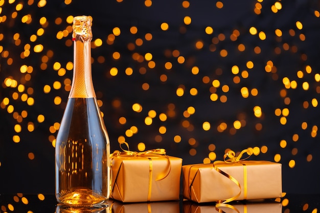 Champagne bottle and wrapped gifts with bokeh lights