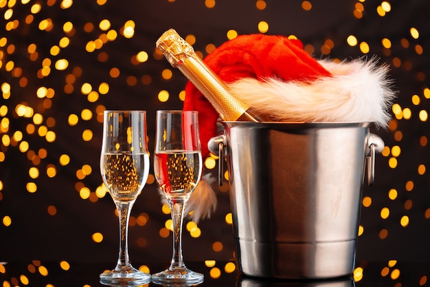 Champagne en kerstman hoed op wazig slinger achtergrond vooraanzicht