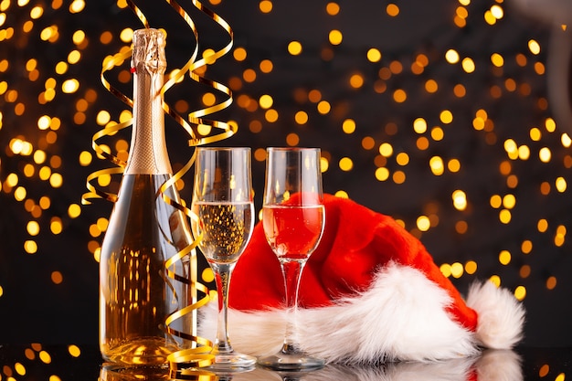 Champagne en kerstman hoed op wazig slinger achtergrond vooraanzicht