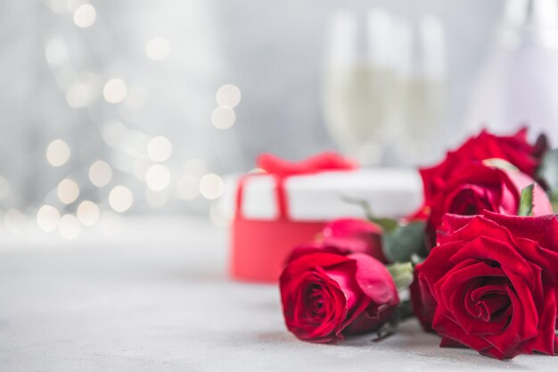 Champagne en rode rozen met bokeh. Valentijnssetting met rode rozen en cadeautje