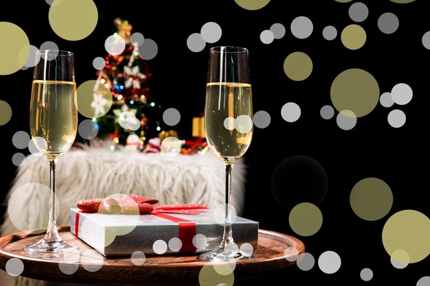 Champagne flutes on table against illuminated christmas lights
