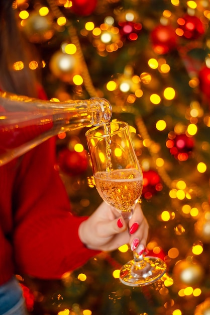 Champagne gieten in een wijnglas mooie kerstboom op de achtergrond