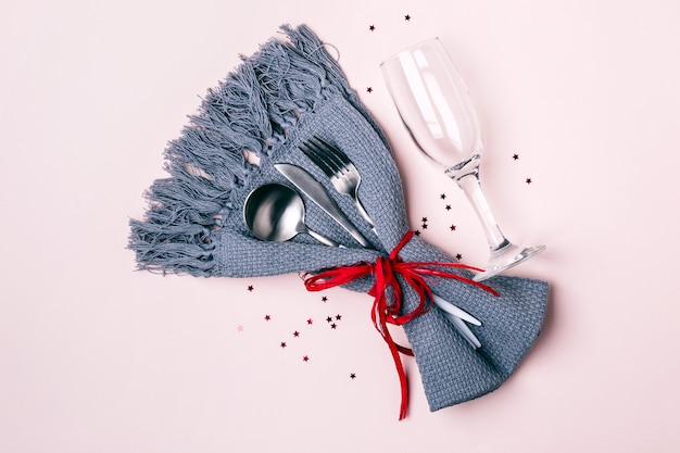 Champagne glass, cutlery and napkin on pink pastel background. Christmas Table Setting.